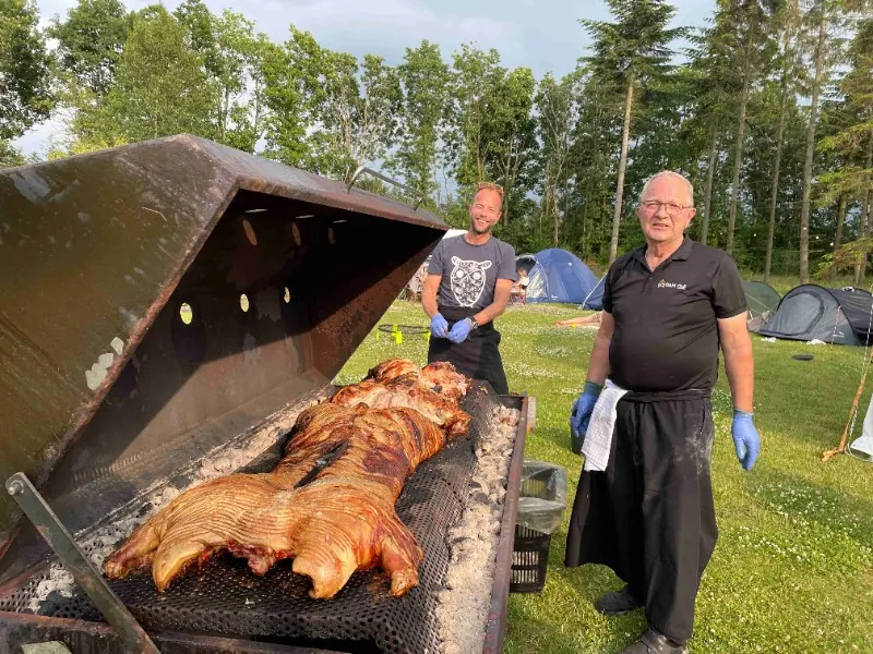 Helstegt pattegris på grillen, mens to kokke holder øje.