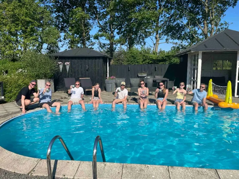 Gæster sidder på kanten af poolen med fødderne i vandet.